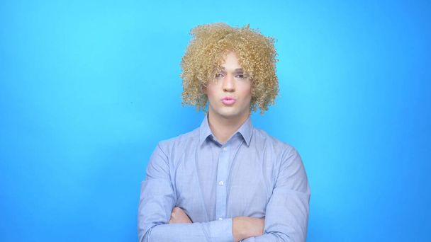 man with makeup and a wig on a blue background . copy space - Valokuva, kuva