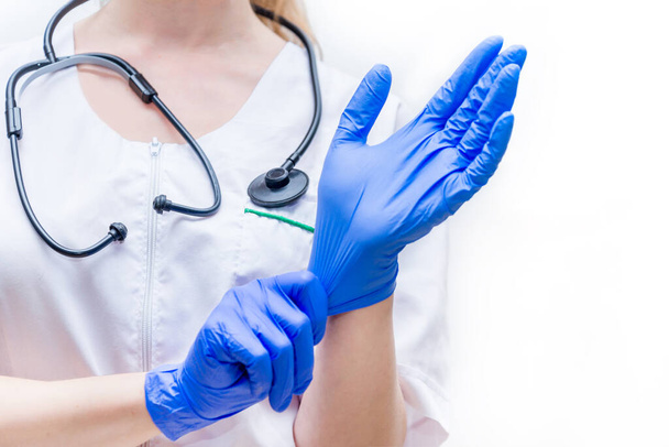 Protecting healthcare workers from infection. A female doctor wears medical gloves on a white isolated background. Personal protective equipment before examination of patients - Foto, afbeelding