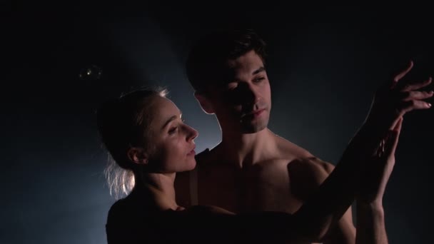 Profesionální, smyslní baletní tanečníci na tmavé scéně v podání sexuálního páru v bílém. Dívají se k sobě s vášní. Láska v očích. Zpomalený pohyb. - Záběry, video