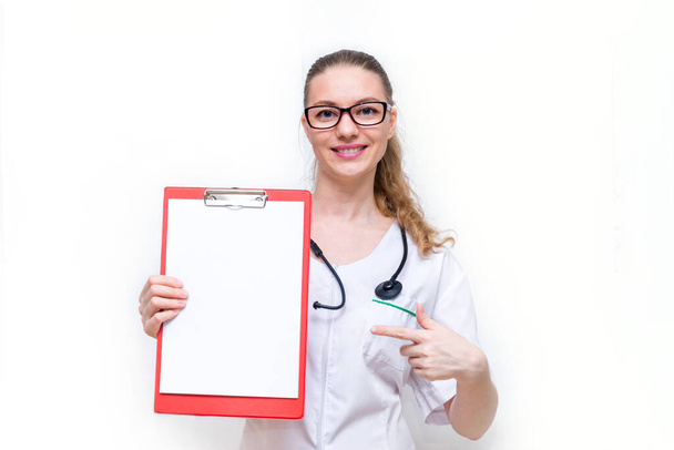 The female doctor happily shows her tablet with paper and smiles. Copy space. Mock up on a white isolated background. Positive information for patients about medicine. The good news, a warm welcome - Zdjęcie, obraz