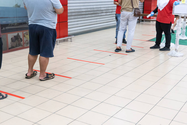 Distanciamento social sendo praticado na entrada para o supermercado na Malásia com 1 metro de diferença entre as pessoas em fila
. - Foto, Imagem