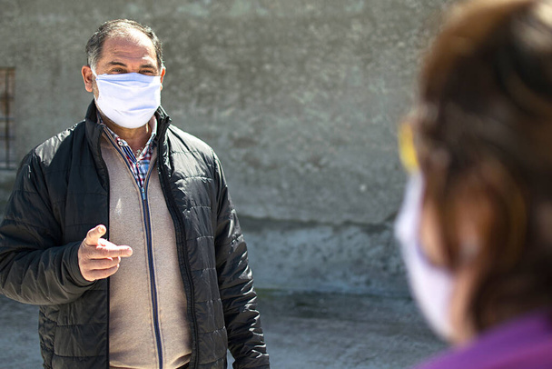 Zwei Gesprächspartner halten Sicherheitsabstand, tragen Schutzmasken gegen Coronavirus oder Covid-19-Virus-Ausbruch in einer Stadt. Coronavirus, Covid-19, Virusausbruch oder soziales Distanzierungskonzept. - Foto, Bild