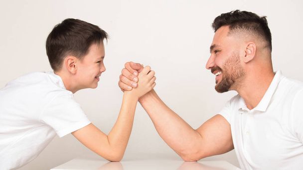 Leikkisä isä ja poika kilpailevat kädenvääntöä
 - Valokuva, kuva
