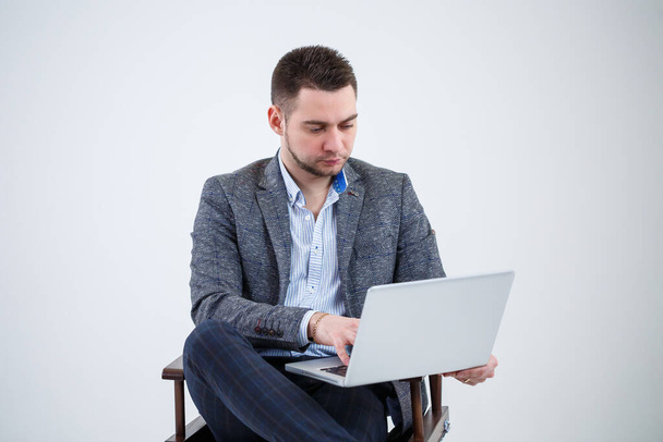 Férfi tanár igazgató üzletember ül egy széken, dokumentumokat tanulmányozva. A laptop képernyőjét nézi. Új üzleti projekt. - Fotó, kép