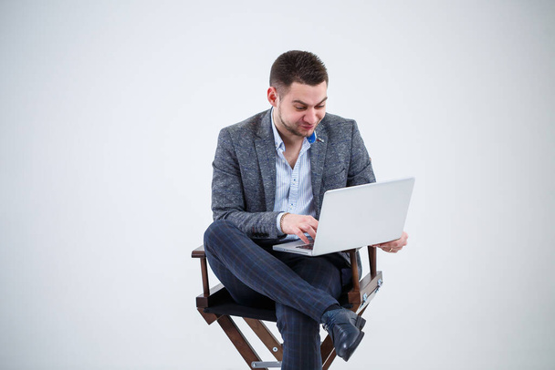 Männlicher Lehrer Direktor Geschäftsmann sitzt auf einem Stuhl und studiert Dokumente. Er blickt auf den Laptop-Bildschirm. Neues Geschäftsprojekt. - Foto, Bild