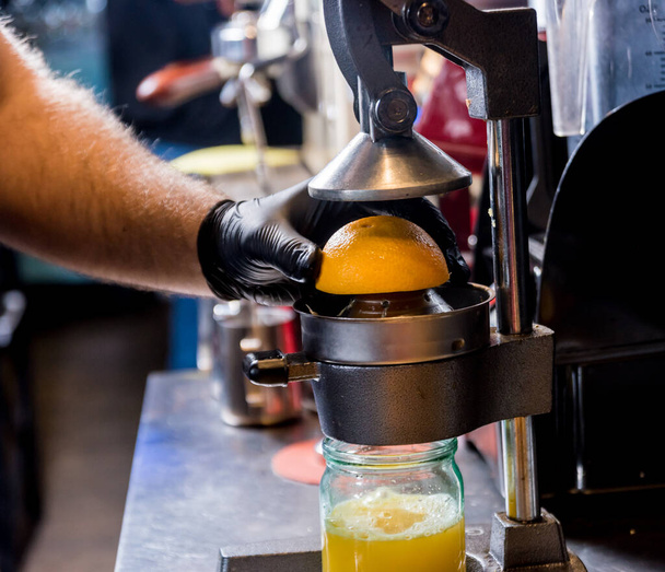 Metal manual juicer. Preparation of freshly squeezed orange juice - Foto, imagen