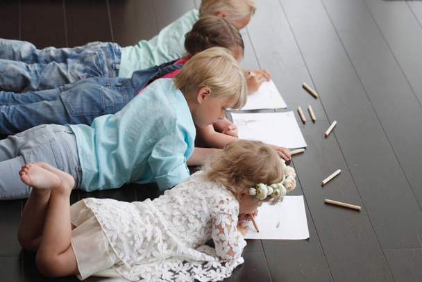 Cute little children friends drawing with pencils at home laying on floor - Photo, Image