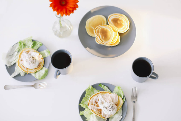 Healthy nutritious tasty breakfast. Pancakes, poached egg on ceramic plate and coffee cup. table setting. food photo. good morning - Photo, image