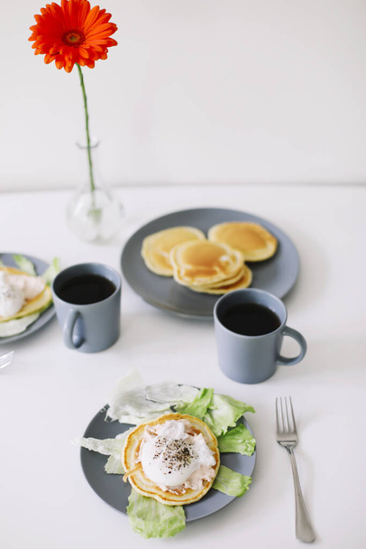 Healthy nutritious tasty breakfast. Pancakes, poached egg on ceramic plate and coffee cup. table setting. food photo. good morning - Photo, image