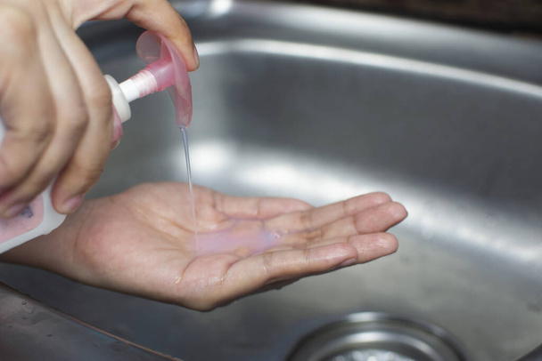 Nainen painamalla nestemäistä saippuaa antibakteerinen kätensä pesuun vastaan infektio sepelvaltimovirus, Covid-19, Hygienia käsite
. - Valokuva, kuva