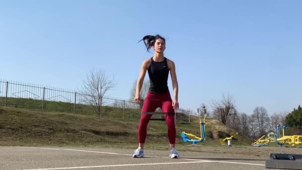 Γυναικεία προπόνηση και γυμναστική στο ύπαιθρο το πρωί. Δυνατή και αθλητική γυναίκα κάνει άλματα, κατάληψη, μπούρδες - Πλάνα, βίντεο