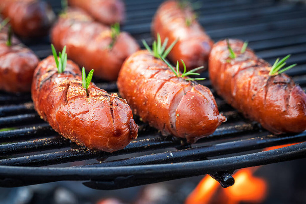 Closeup van heerlijke worst op grill met specerijen en kruiden - Foto, afbeelding