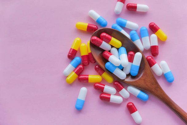 Zblízka barevné pilulky na lžíci na růžovém pozadí  - Fotografie, Obrázek