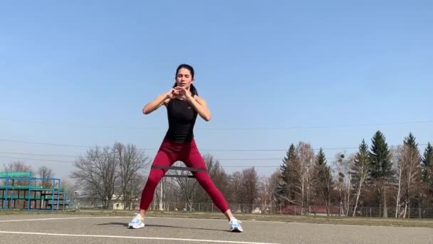 Γυναικεία προπόνηση και γυμναστική στο ύπαιθρο το πρωί. Δυνατή και αθλητική γυναίκα κάνει άλματα, κατάληψη, μπούρδες - Πλάνα, βίντεο