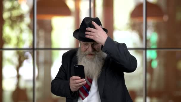Extrem aufgeregter alter Mann im Anzug hat Spaß mit Smartphone. - Filmmaterial, Video