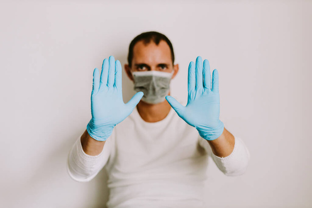 чоловік носить латексні медичні рукавички та маску для обличчя вдома для запобігання вірусу. Статус в домашніх умовах ізоляції
. - Фото, зображення