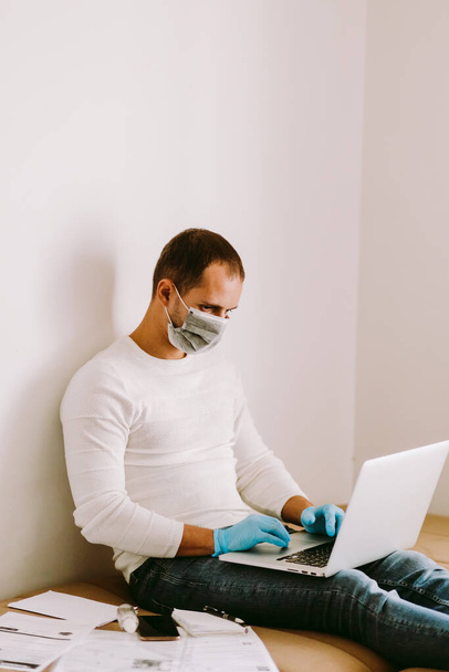 férfi laptoppal és okostelefonnal karantén alatt otthon. A koncepció a SELF-ISOLATION férfi dolgozik otthon a koronavírus COVID-19. - Fotó, kép