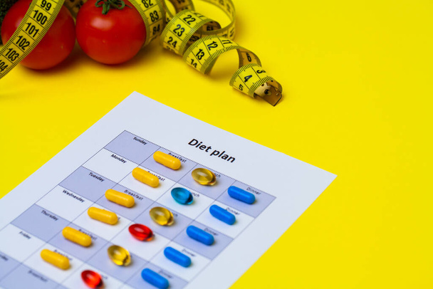 Táplálkozási terv fogyás tabletták és friss zöldségek sárga alapon. - Fotó, kép