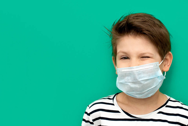 Egy fiú orvosi maszkban izolálva a coronovírus alatt. A meglepetés érzései. Másold a helyet. Zöld szín. - Fotó, kép