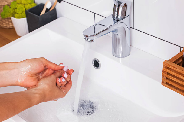 Woman washing her hands with soap in a white bathroom - Фото, зображення