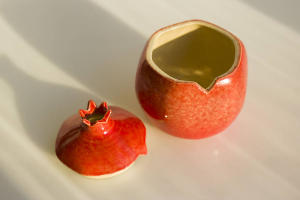 rode keramische granaatappel. vaas, kist, decor, kunstvoorwerp voor het interieur. granaatappel - een symbool van gezondheid, vruchtbaarheid en familie. met deksel - Foto, afbeelding