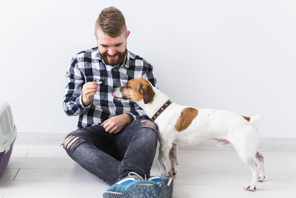 Dog carrying bags and pets owner concept - Attractive cheerful male in plaid shirt holds favourite pet. Happy bearded man with his jack russell terrier - Foto, imagen