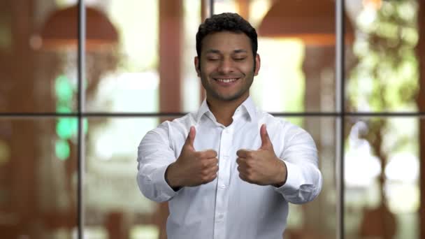 Portret młodego hinduskiego mężczyzny w białej koszuli z kciukami w górze. - Materiał filmowy, wideo