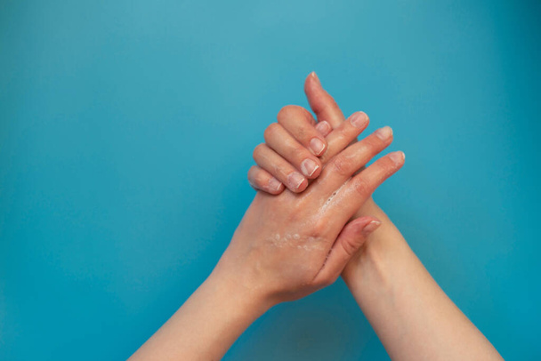 Жінка використовує мило і миття рук ізольовано на синьому фоні. Подробиці гігієни. гігієна рук миття рук з милом у гарячій воді для захисту від коронавірусних мікробів
. - Фото, зображення