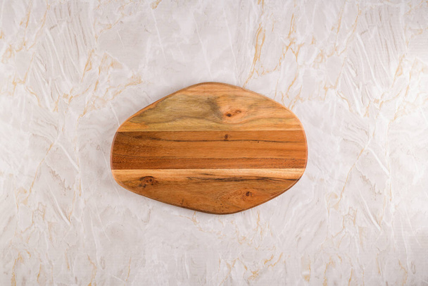 Top view of wooden cutting board on a gray marble background with space for text. - Фото, изображение