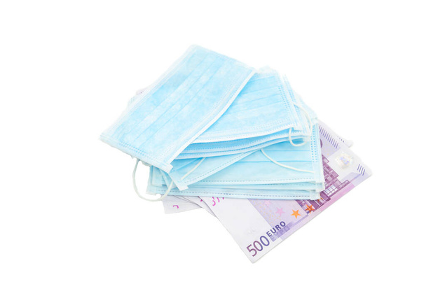 A pack of medical mask lies on 500 euro banknotes. The concept of buying a mask in Europe for a lot of money, virus protection, lack of protection. Isolated white background - Foto, afbeelding