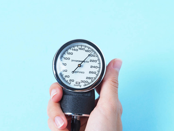 la main d'une femme tient un tensiomètre qui montre la pression artérielle. Gros plan, fond bleu. Concept de médecine
 - Photo, image