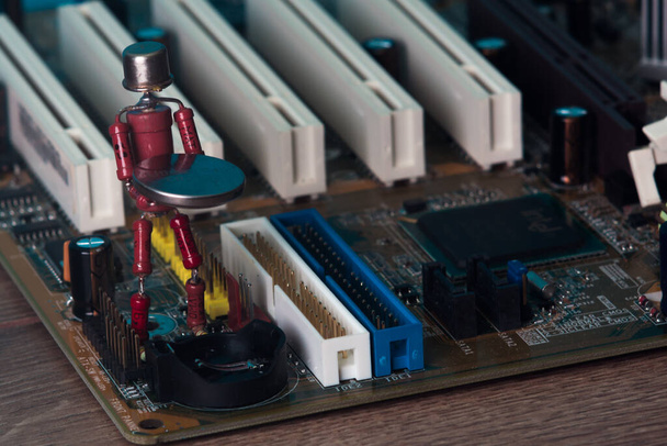 kleine menschliche Figur, die aus Widerständen und Transistoren besteht, hilft elektronische Computerplatine zu fixieren - Foto, Bild