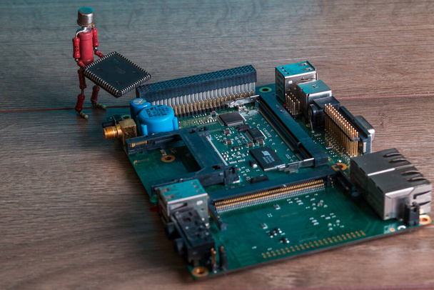 pequeña figura humana, hecha de resistencias y transistor, ayuda a fijar la placa de computadora electrónica
 - Foto, imagen