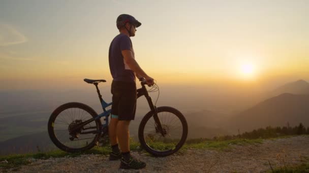 SUN FLARE άνθρωπος στέκεται δίπλα στο ποδήλατο βουνού του, ενώ παρατηρώντας την ηλιόλουστη φύση - Πλάνα, βίντεο
