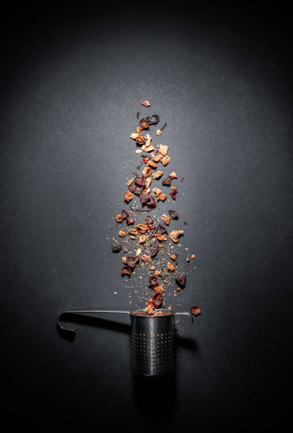 Fruit tea of dried flowers petals and dry berries with strainer or infuser- filter isolated on gray black background. Blank free space for your advertising or text. Copyspace - Foto, immagini