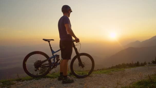 COPY SPACE: Onherkenbare man kijkt naar de zonsopgang voor een mountainbike rit. - Video