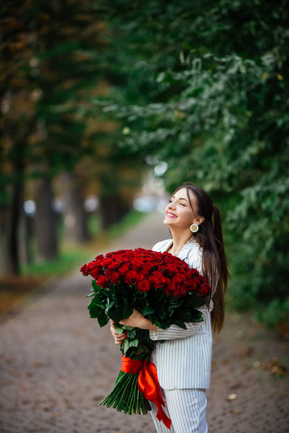 Young Beauty Smelling Bouquet of Red Roses. Pleasure & Harmony. - Photo, Image