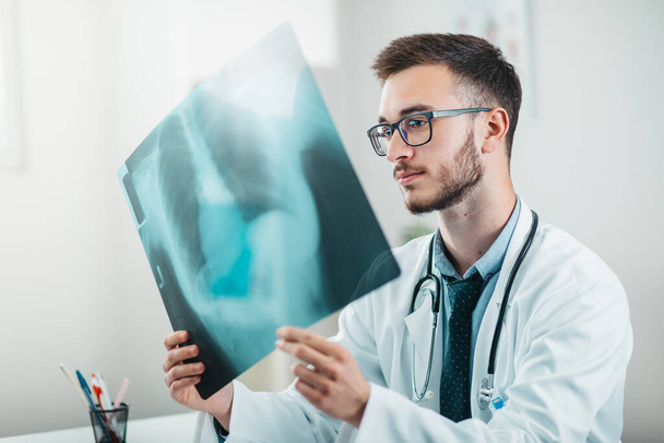 Portrait of Young Radiologist on the Job looking at x-ray. Volunteer at the hospital gains practical knowledge in treating disease - Фото, зображення
