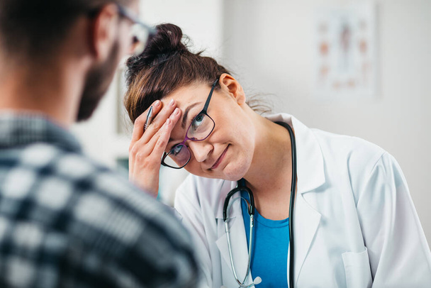La doctora siente pena por compartir malas noticias con un paciente joven sobre su enfermedad
 - Foto, Imagen