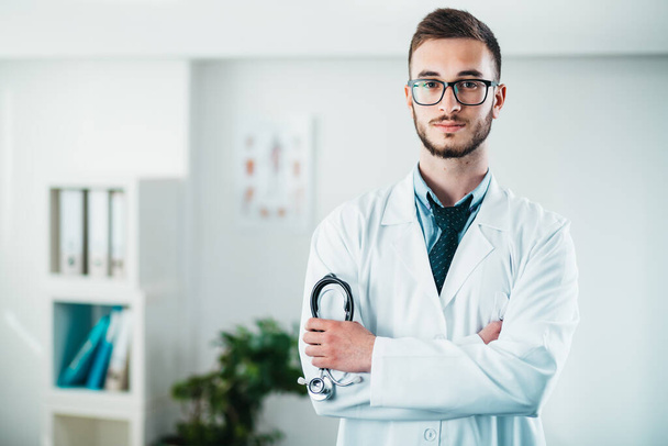 Portrait of Doctor holding a stethoscope with crossed arms at the hospital - 写真・画像