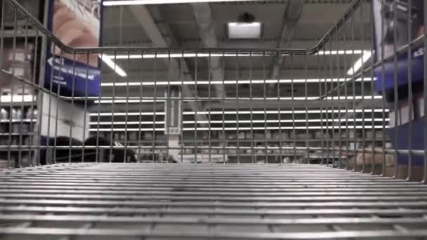 Kijken naar een winkelwagentje in een supermarkt gangpad met eetplanken - Video