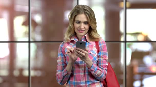 Νέα ξανθιά περιστασιακή κοπέλα γραπτών μηνυμάτων σε κάποιον στο smartphone της. - Πλάνα, βίντεο