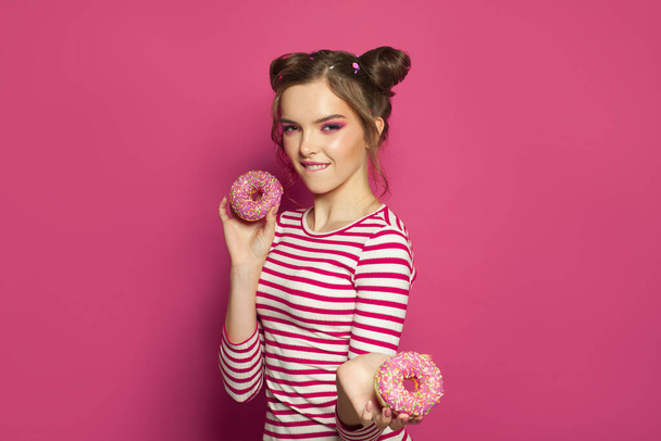 Vicces lány és fánk színes rózsaszín háttér, diéta koncepció - Fotó, kép
