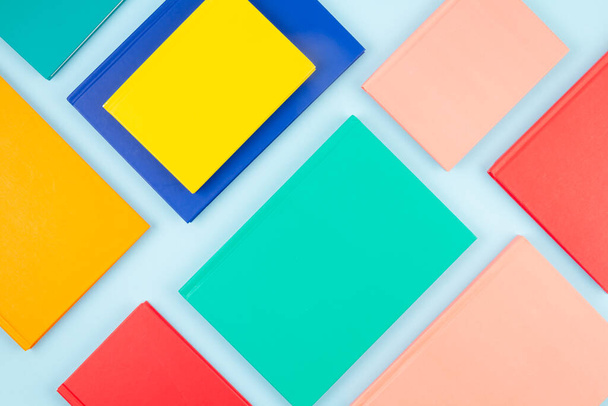 Bovenaanzicht van kleurrijke notitieboekjes over de blauwe pastelachtergrond. Moderne abstracte werkruimte, studies, kantoorconcept - Foto, afbeelding