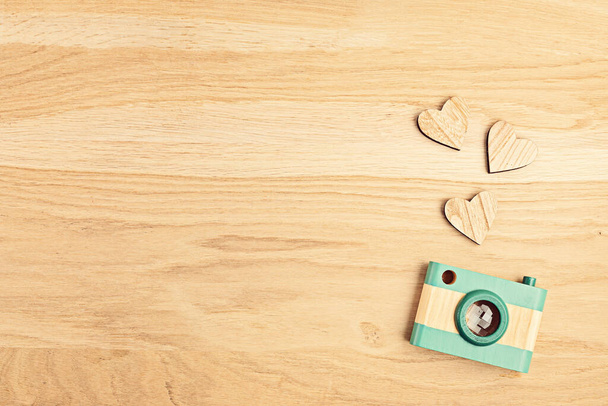 Flat lay with toy wooden camera and hearts over wooden background. Social media, posts, likes, followers, online photography classes concept. Top view, copy space. - Photo, Image