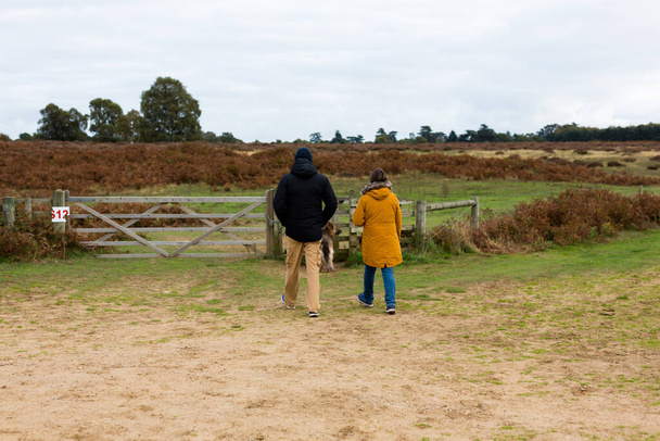 Una pareja de mediana edad llevando a su perro a dar un paseo por el campo - Foto, imagen