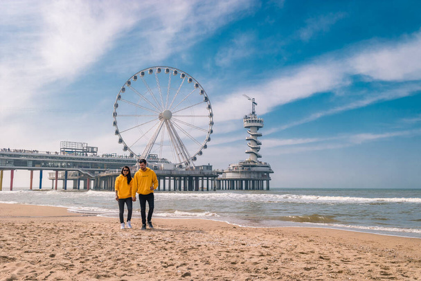 coppia sulla spiaggia di Schevening Olanda durante la primavera, The Ferris Wheel The Pier at Scheveningen in Netherlands, Sunny spring day at the beach
 - Foto, immagini