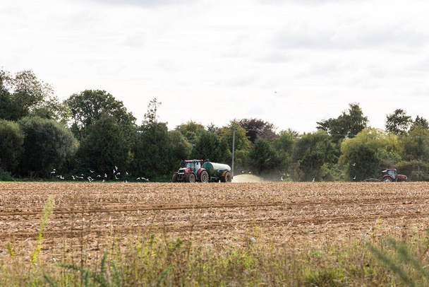 Egy traktor, ami hígtrágyát és trágyát terjeszt a mezőn, készen áll új termés ültetésére. - Fotó, kép