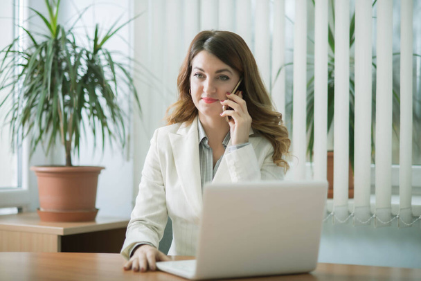Ділова жінка в офісі компанії працює на ноутбуці онлайн і віддалено спілкується
 - Фото, зображення