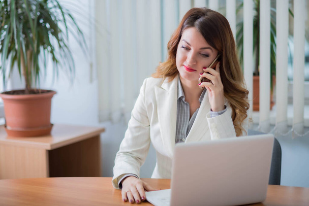 Business nainen yrityksen toimistossa työskentelee kannettavan tietokoneen verkossa ja kommunikoida etänä
 - Valokuva, kuva